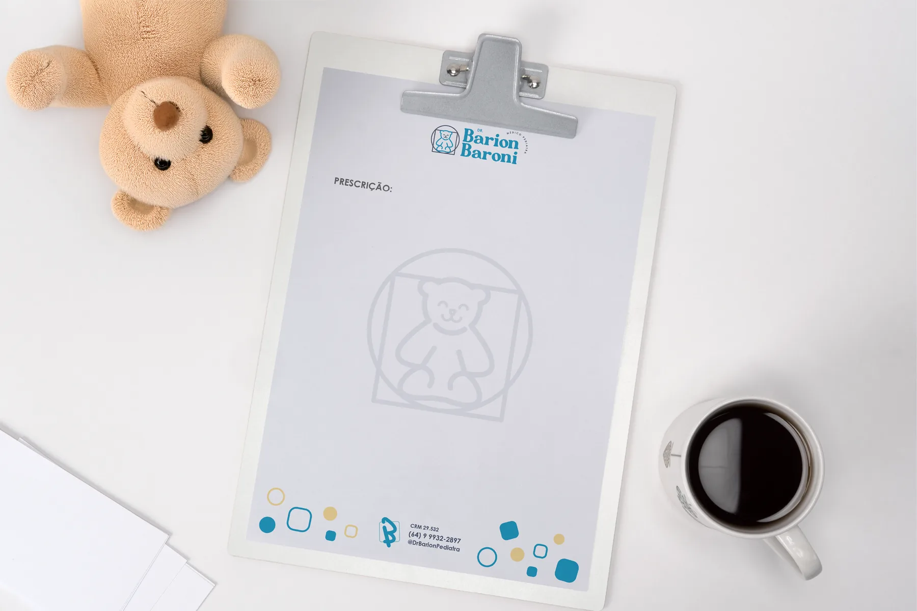 Receituário timbrado sobre prancheta, ao lado de um urso de pelúcia e uma xícara de café